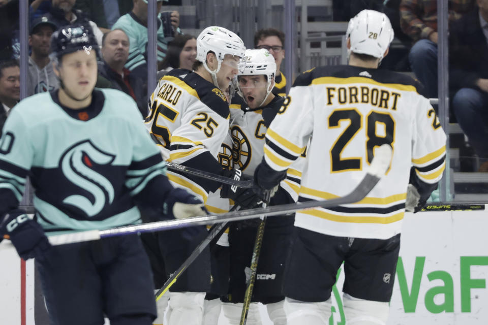 Boston Bruins center Patrice Bergeron celebrates his goal against the Seattle Kraken with defenseman Brandon Carlo (25) during the second period of an NHL hockey game Thursday, Feb. 23, 2023, in Seattle. (AP Photo/John Froschauer)