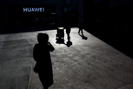 FILE PHOTO - People walk past a Huawei shop in Beijing, China, December 11, 2018. REUTERS/Thomas Peter/File Photo