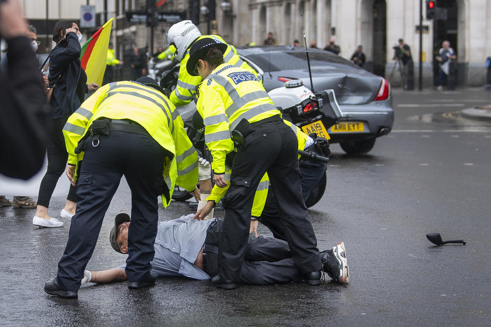 Police detain a man after he ran in front of Prime Minister Boris Johnson's car (in background with dent) as it left the Houses of Parliament, Westminster. The man, who had been demonstrating about Turkey's operation against Kurdish rebels in northern Iraq, was taken into the Palace of Westminster by officers.