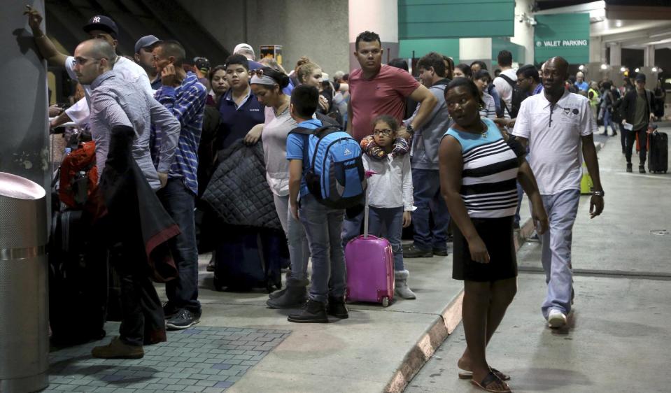 Passengers wait in line at Terminal 4 after the airport opened at 5:00 a.m. at Ft. Lauderdale-Hollywood International Airport, Saturday, Jan. 7, 2017, the day after a shooting in the baggage area. Authorities say Army veteran Esteban Santiago of Anchorage, Alaska, drew a gun from his checked luggage on arrival and opened fire on fellow travelers. (Mike Stocker/South Florida Sun-Sentinel via AP)