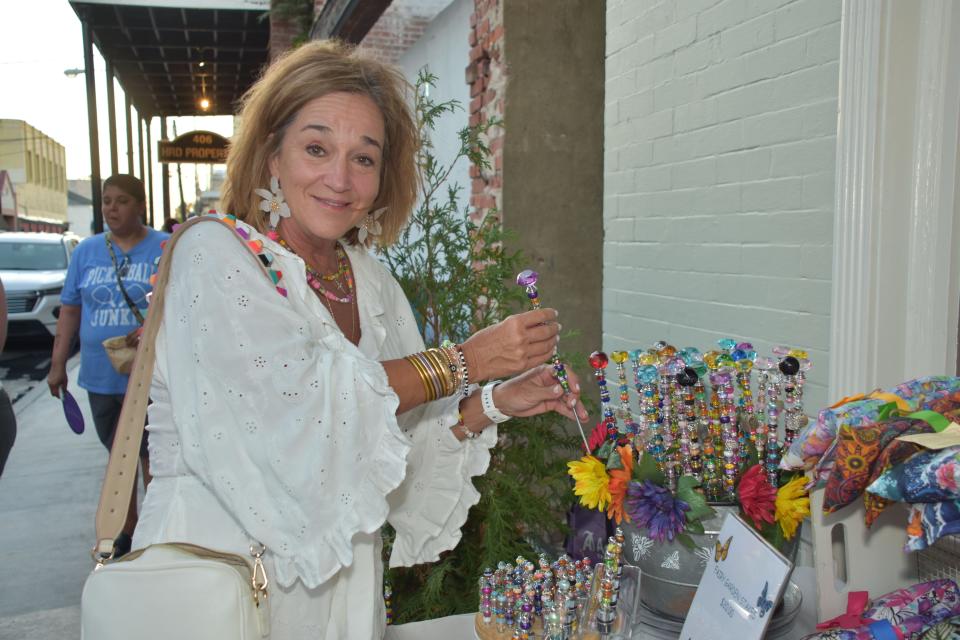 Karen Mire looks at decorated garden stakes at the Creations by Ann's booth during Cajun Linen Night in downtown Thibodaux Aug. 11.