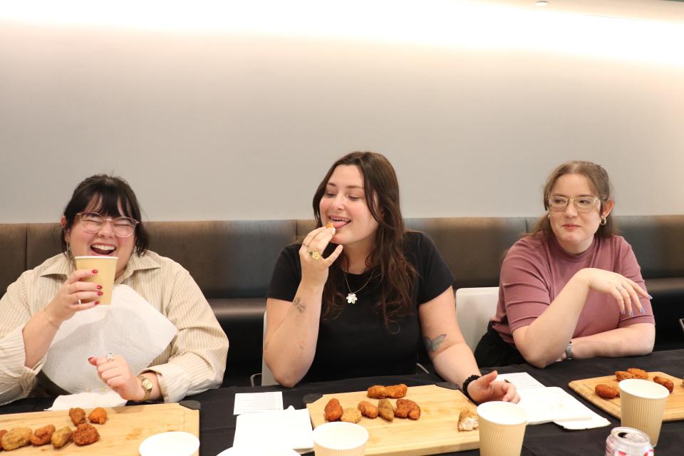 Three of Insider's reporters eating chicken wings at a table.