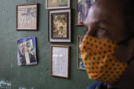 Marcio Antonio do Nascimento stands next to a framed childhood image of his 25-year-old son Hugo do Nascimento who died from the new coronavirus, in Rio de Janeiro, Brazil, Saturday, Aug. 1, 2020. Brazil was leaping toward a grim milestone, 100,000 deaths from COVID-19, on Saturday, Aug. 8, and five months after the first reported case, the country had not shown signs of crushing the disease. (AP Photo/Leo Correa)