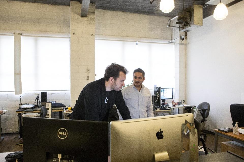 In this Dec. 19, 2013 photo, Bitstrips CEO and Creative Director Jacob Blackstock, left, and co-founder Shahan Panth work at the company's offices in Toronto. Bitstrips, a mobile application that helps people turn their lives into comic strips, may seem like a sudden sensation now that its vignettes are all over Facebook and other social networks. But the Toronto startup’s success has been a drawn-out process. (AP Photo/The Canadian Press, Chris Young)