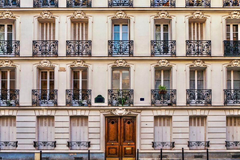 Street view of the elegant facade of an old apartment building in a residential neighborhood of Paris. Vintage style photo.