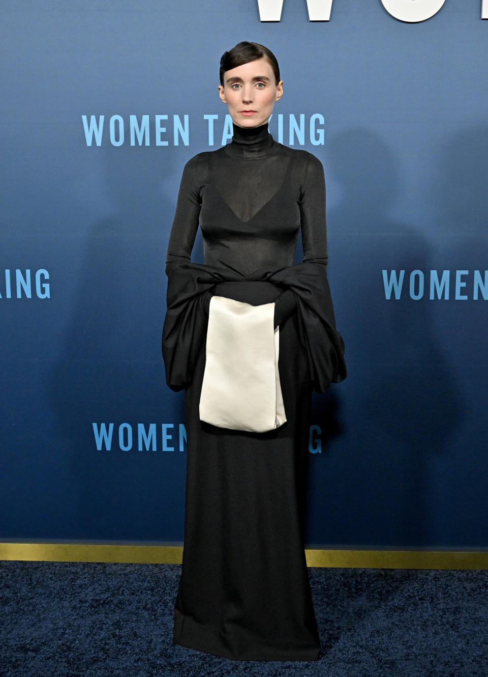 Rooney wears a long-sleeved turtleneck dress on the red carpet for an event