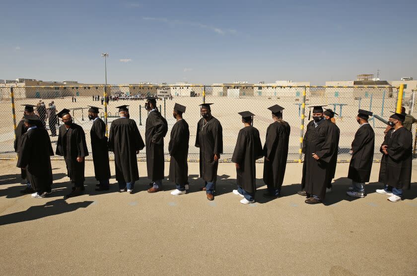 LANCASTER, CA - OCTOBER 05: Graduates of Cal State LA's Prison B.A. Program enter the prison yard before their ceremony inside the California State Prison in Lancaster. A ceremony followed the graduation events for classmates whose sentences were commuted. The program is the first of its kind in California. California State Prison on Tuesday, Oct. 5, 2021 in Lancaster, CA. (Al Seib / Los Angeles Times).