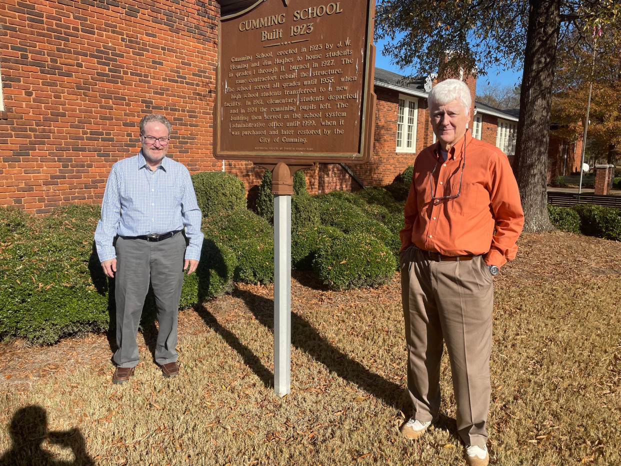 Historical Society of Cumming/Forsyth County leaders Jimmy McConnell and George Pirkle in front of the Cumming Public School, the county's oldest brick school.