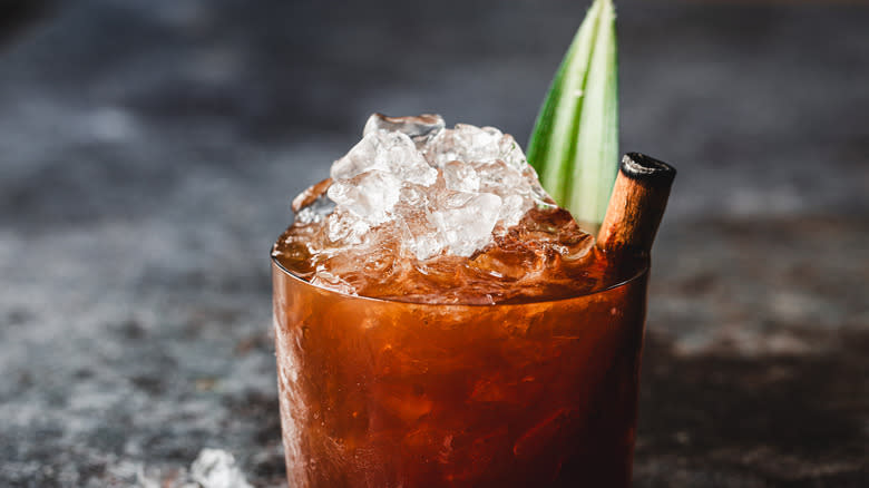 Red cocktail with ice and pineapple leaf