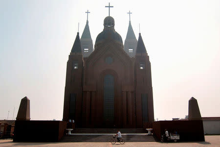 A man rides his bicycle past the steps of a large Catholic church in the village of Bai Gu Tun, located on the outskirts of the city of Tianjin, around 70 km (43 miles) south-east of Beijing July 17, 2012. REUTERS/David Gray/File Photo