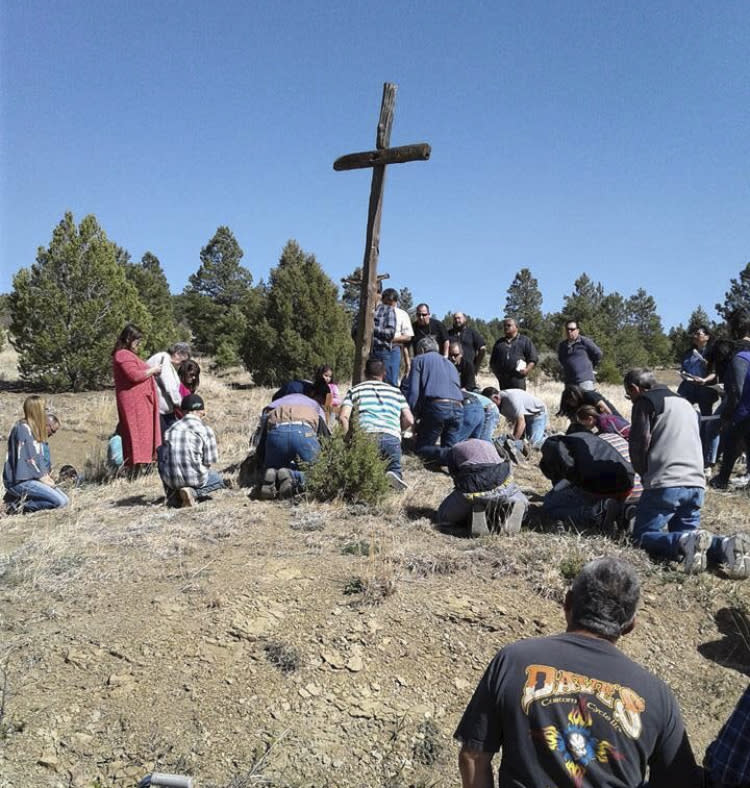 This April 14, 2017, photo provided by Fidel Trujillo shows a group praying at the foot of a cross on Good Friday in Holman, New Mexico. Residents of the community were forced to evacuate because of a wildfire that has marched across 258 square miles of high alpine forest and grasslands at the southern tip of the Rocky Mountains. (Fidel Trujillo via AP)