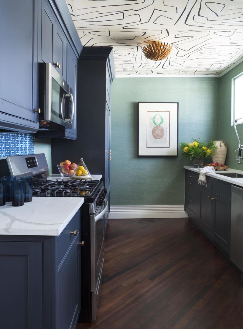 green kitchen with blue cabinets and white and black patterned wallpaper on ceiling