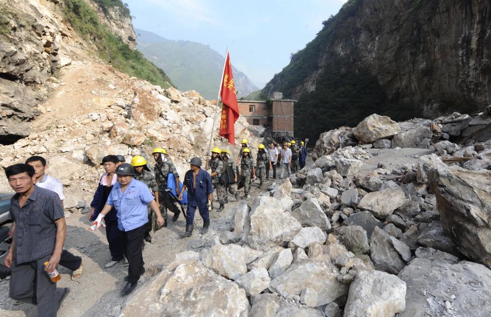 In this Saturday, Sept. 8, 2012 photo released by China's Xinhua News Agency, rescuers walk to the Luozehe Village, one of the hardest-hit areas struck by Friday's quakes, in Yiliang County, southwest China's Yunnan Province. Rescue workers cleared roads Saturday so they could search for survivors and rush aid to the remote mountainous area of southwestern China after twin earthquakes killed at least 80 people. (AP Photo/Xinhua, Qin Qing) NO SALES