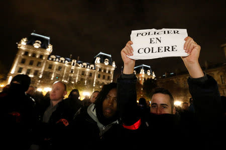 A policeman holds up a sign that reads, "angry police" as he joins other police officers in an unauthorised protest against anti-police violence in front of the Police Prefecture in Paris, France, October 21, 2016. REUTERS/Jacky Naegelen