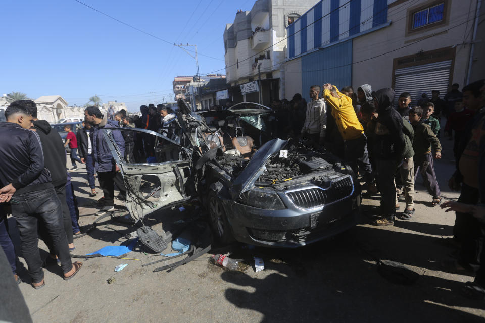 Palestinians look at a car targeted by an Israeli airstrike in Rafah, Gaza Strip, Sunday, Jan. 7, 2024. Two journalists were killed in the strike, Hanza Dahdouh, who worked for Al Jazeera, and a freelance journalist, Mustafa Thuria (AP Photo/Hatem Ali)