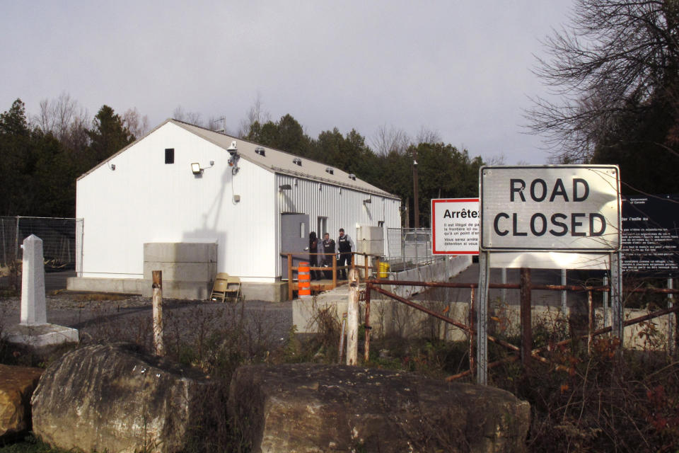 In this Nov. 4, 2019, photo, a woman is led into a building by officers from the Royal Canadian Mounted Police in Saint-Bernard-de-Lacolle, Quebec, after illegally crossing the border from the United States at Roxham Road in Champlain, N.Y. Since early 2017, when people who despaired of finding a permanent safe haven in the United States began turning to Canada for help, around 50,000 people have illegally entered Canada, many through Roxham Road in upstate New York. A case being heard in a Toronto court this week could end the use of Roxham Road. (AP Photo/Wilson Ring)