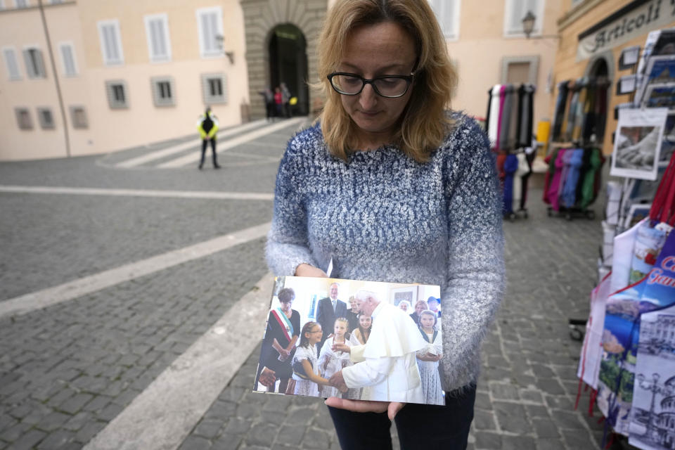 Patrizia Gasperini a shopkeeper of Castel Gandolfo, near Rome, shows a photo of the late Pope Emeritus Benedict XVI with her daughter Benedetta, during an interview with the Associated Press, Tuesday Jan. 3, 2023. Benedict's death has hit Castel Gandolfo's "castellani" particularly hard, since many knew him personally, and in some ways had already bid him an emotional farewell on Feb. 28, 2013, when he uttered his final words as pope from the palace balcony overlooking the town square. (AP Photo/Alessandra Tarantino)