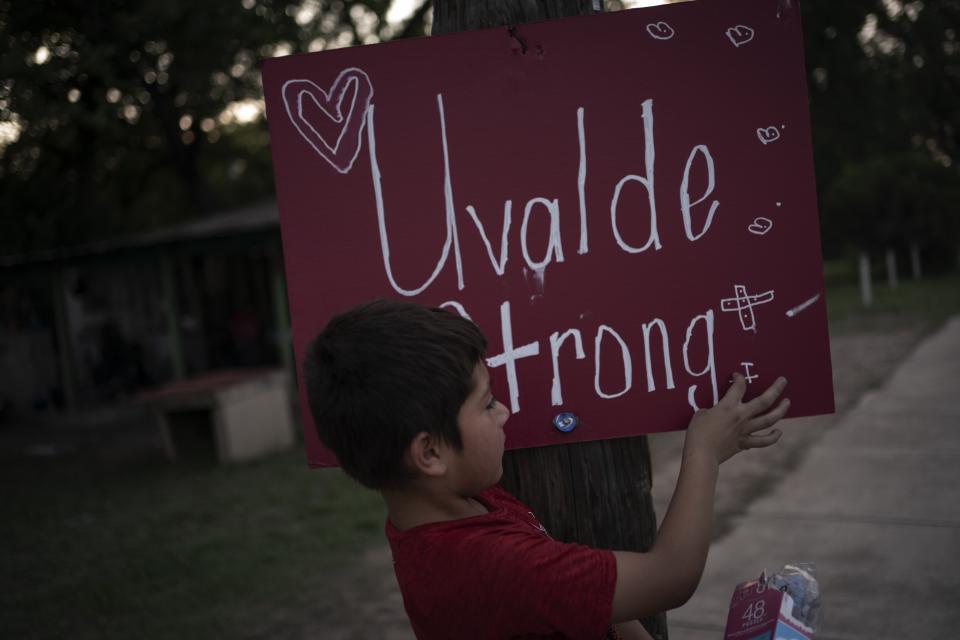 Eight-year-old Jeremiah Lennon picks at a sign that reads "Uvalde Strong" which he helped decorate and stuck on an electric pole in front of his home on Saturday, May 28, 2022, in Uvalde, Texas. The third grader had been in classroom 112, just next to the rooms where the shooter holed up. The 15 kids in his class sat on the ground in the corner, as quiet as they could be, he said. The gunman tried to get in but the door was locked. (AP Photo/Wong Maye-E)