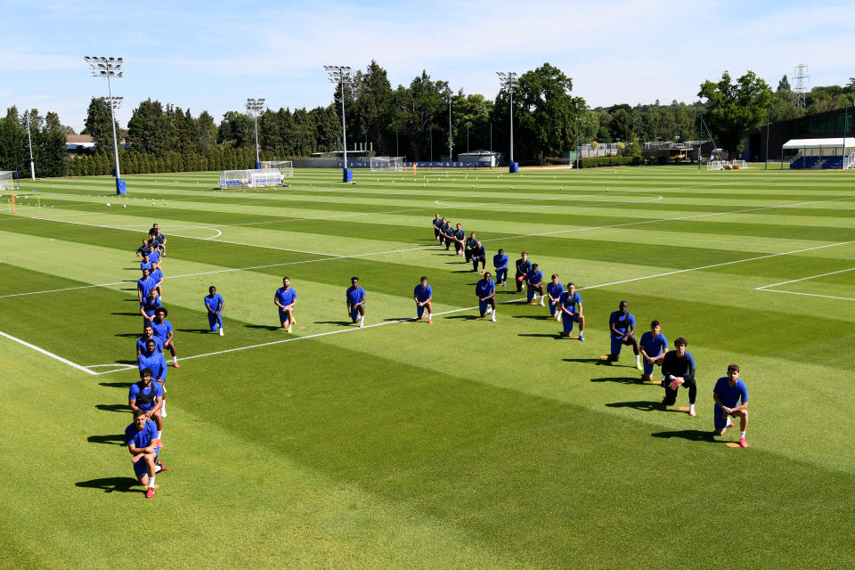 Jugadores del Chelsea arrodillados y alineados para formar una letra H en el césped de su campo de entrenamiento