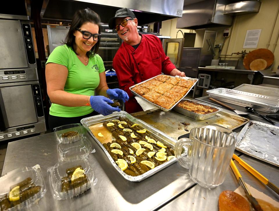 Irene Paleologos of Orange County, N.Y., and Paul Barber, owner of the Flying Rhino restaurant in Worcester, get dolmades (stuffed grape leaves), spanakopita (spinach pie) and moussaka (eggplant casserole) ready for serving Saturday during the St. Spyridon Grecian Festival in Worcester.