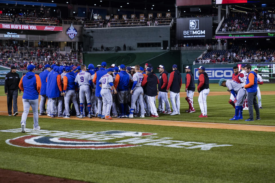 Washington Nationals and New York Mets scuffle after New York Mets' Francisco Lindor, bending over at right, was hit by a pitch from Washington Nationals relief pitcher Steve Cishek during the fifth inning of a baseball game at Nationals Park, Friday, April 8, 2022, in Washington. (AP Photo/Alex Brandon)