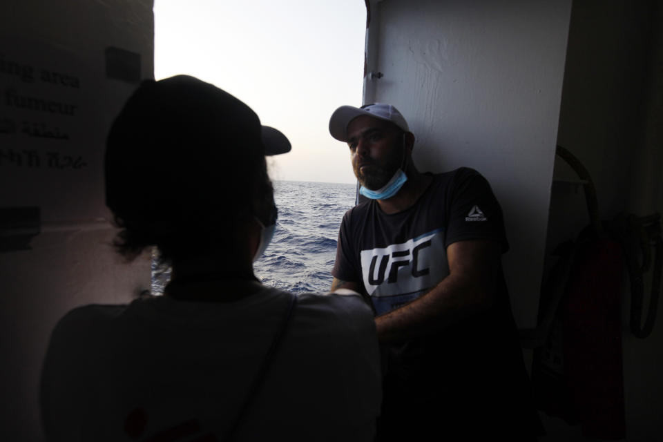 Waleed, a Tunisian migrant, speaks to a humanitarian worker on the deck of the Geo Barents, a rescue vessel operated by MSF (Doctors Without Borders) off Libya, in the central Mediterranean route, Wednesday, Sept. 22, 2021. (AP Photo/Ahmed Hatem)