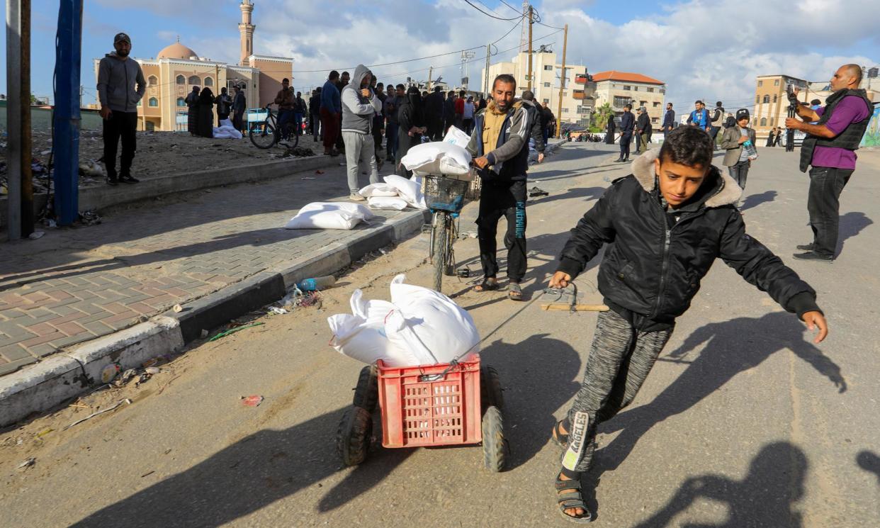 <span>Palestinians carry away flour distributed by Unrwa in Rafah, Gaza, late last year.</span><span>Photograph: Anadolu/Getty Images</span>