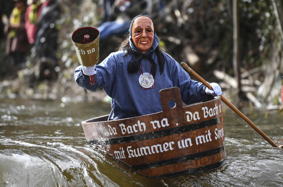 Start driver Peter Zuber rides on the Schiltach during the Da-Bach-na ride as part of the carnival in Rottweil, Germany, Monday, Feb. 24, 2020. 40 participants drove with their 'Zuberboote' on the 400 meter long course. (Patrick Seeger/dpa via AP)