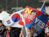 A demonstrator holds a national flag and sign with a picture of South Korea's Justice Minister Cho Kuk during a rally in Seoul, South Korea, Wednesday, Oct. 9, 2019. Thousands of protesters rallied Wednesday in South Korea's capital for the second consecutive week to call for the ouster of President Moon Jae-in's hand-picked justice minister, whose family is at the center of an investigation into allegations of financial crimes and academic favors. (AP Photo/Lee Jin-man)