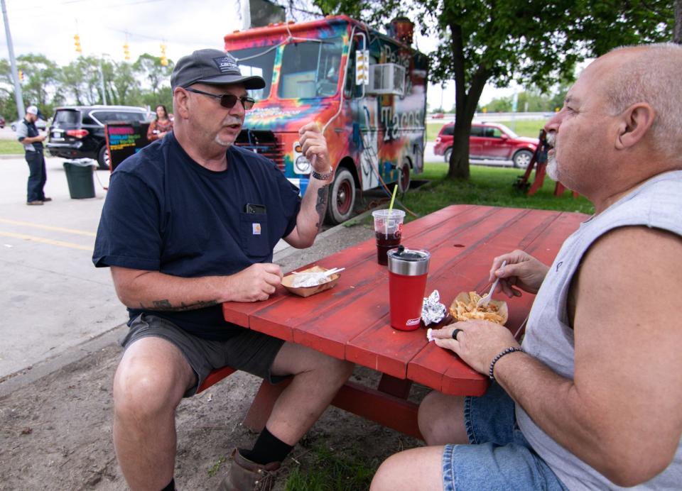 Bob Aldrich of Commerce, left, and Wolverine Lake resident Jamie Schneider try Peace, Love & Tacos for the first time Monday, May 23, 2022. The food truck is parked in the parking lot of a BP gas station at 8340 Grand River Ave. in Brighton.