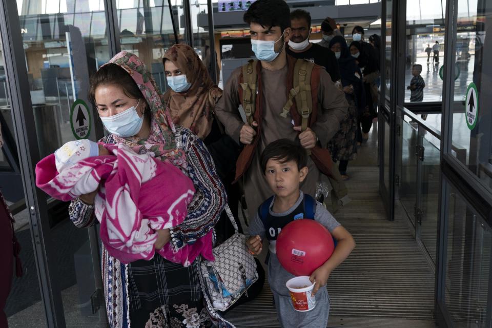 Families evacuated from Kabul, Afghanistan, walk through the terminal before boarding a bus after they arrived at Washington Dulles International Airport, in Chantilly, Va., on Friday, Aug. 27, 2021. (AP Photo/Jose Luis Magana)