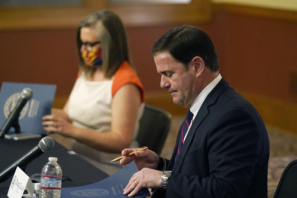 Arizona Secretary of State Katie Hobbs, left, and Arizona Gov. Doug Ducey sign election documents to certify the election results for federal, statewide, and legislative offices and statewide ballot measures at the official canvass at the Arizona Capitol Monday, Nov. 30, 2020, in Phoenix. (AP Photo/Ross D. Franklin, Pool)