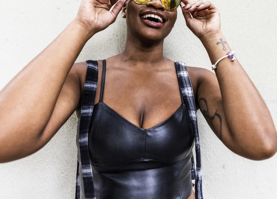 A woman wears sunglasses and a patent leather black tank top