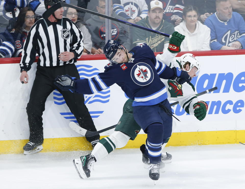 Winnipeg Jets' Neal Pionk (4) and Minnesota Wild's Mason Shaw (15) collide during the second period of an NHL hockey game, Wednesday, March 8, 2023 in Winnipeg, Manitoba. (John Woods/The Canadian Press via AP)
