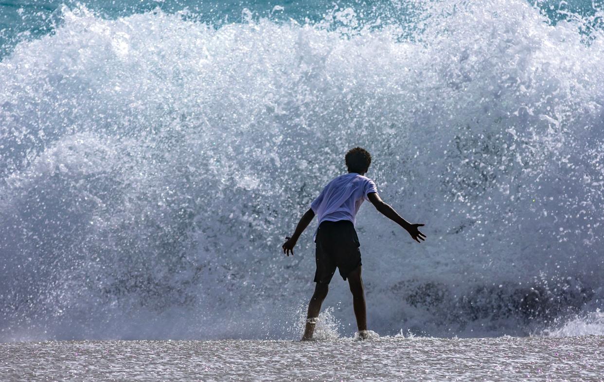 A boy stops short of entering the Atlantic Ocean at Midtown Beach as a massive wall of water approaches him Wednesday morning March 27, 2024.