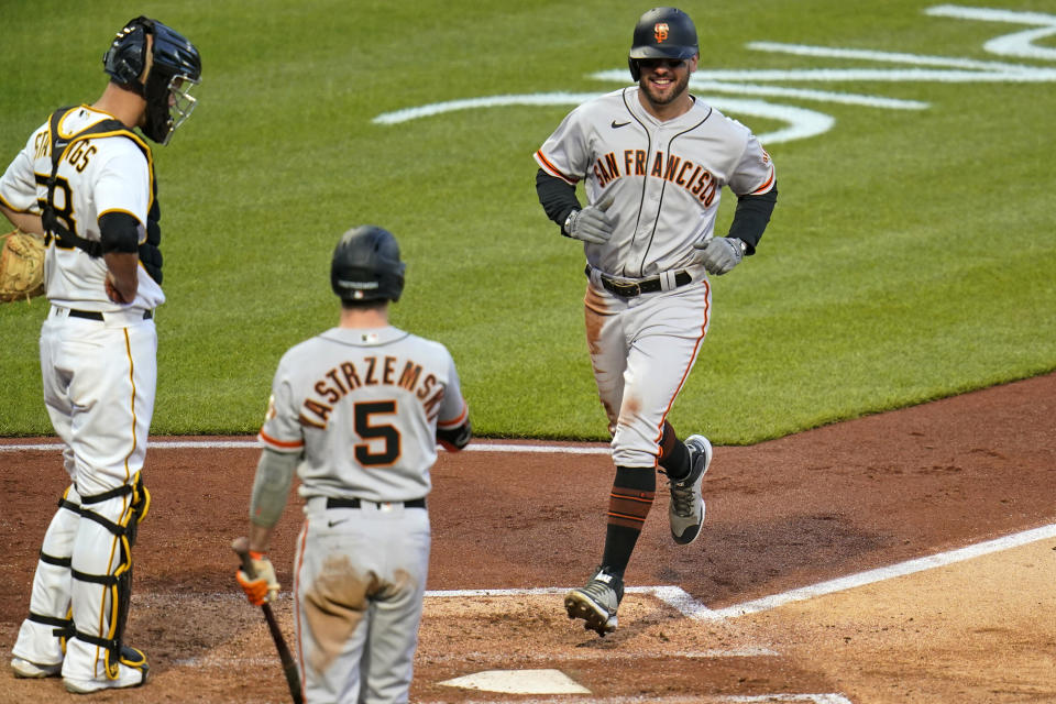 San Francisco Giants' Mike Tauchman, right, scores on an errant pickoff throw to third base by Pittsburgh Pirates catcher Jacob Stallings, left, during the fifth inning of a baseball game in Pittsburgh, Thursday, May 13, 2021.(AP Photo/Gene J. Puskar)