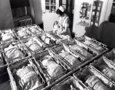 FILE - In this 1930 file photo, a nurse holds a baby in the nursery of the Pennsylvania Hospital in Philadelphia. Five years after the deepest global recession since the 1930s sent birth rates plunging around the world, many couples are still not having children. That’s good news if you’re worried about an overcrowded planet. But it’s bad for the economy. (AP Photo/File)
