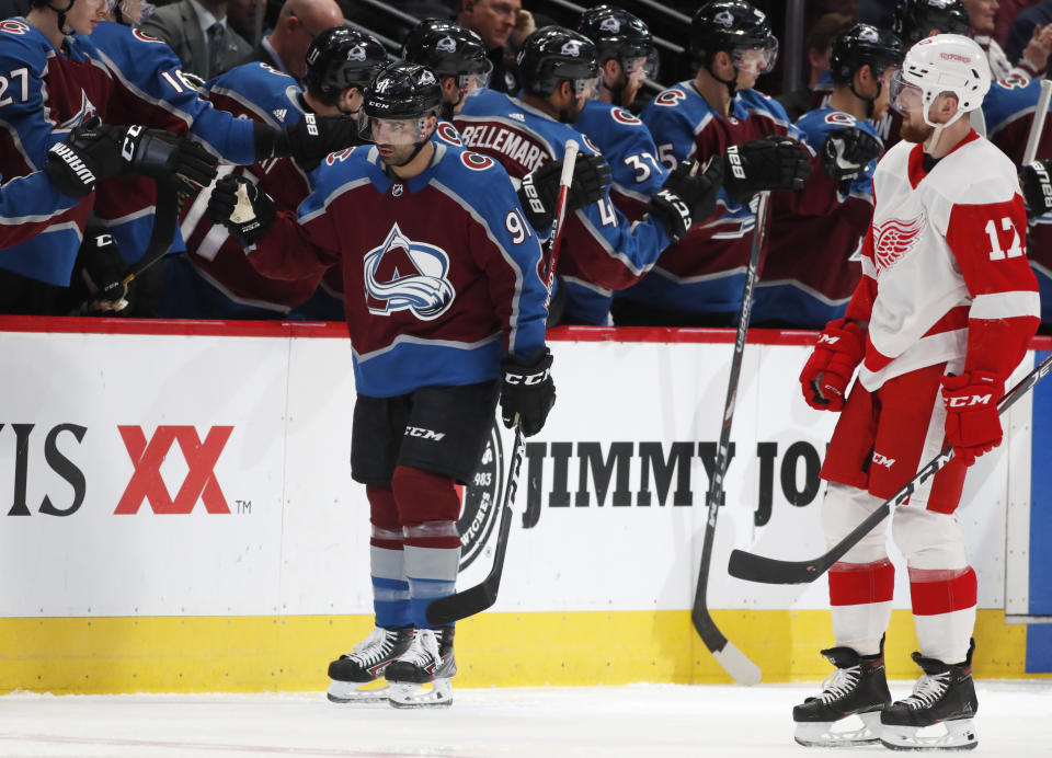 Colorado Avalanche center Nazem Kadri, back, is congratulated as he passes the team box after scoring a goal as Detroit Red Wings defenseman Filip Hronek looks on in the second period of an NHL hockey game Monday, Jan. 20, 2020, in Denver. (AP Photo/David Zalubowski)