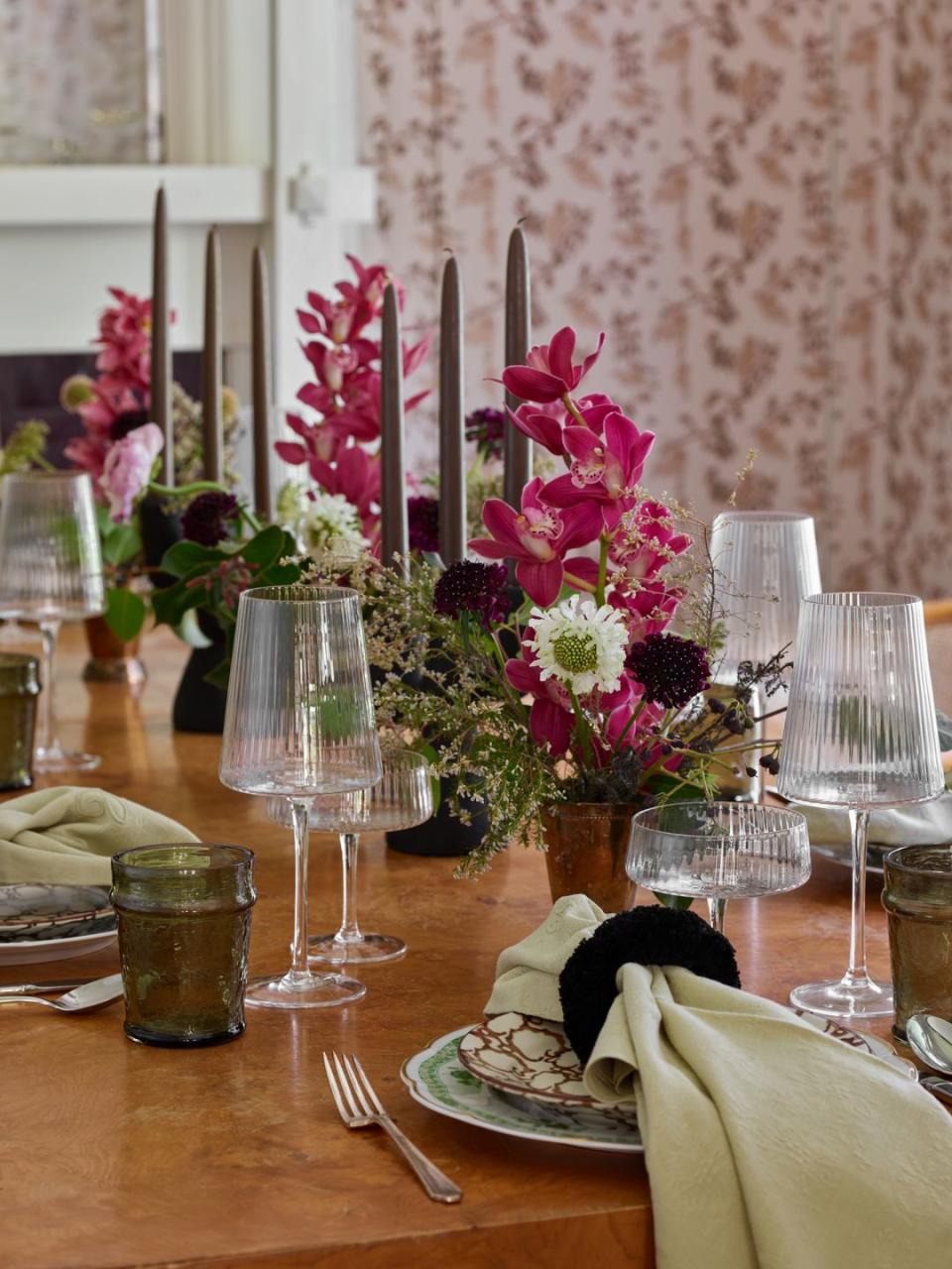 green and brown plates on a table with pink orchids and an arrangement of wildflowers