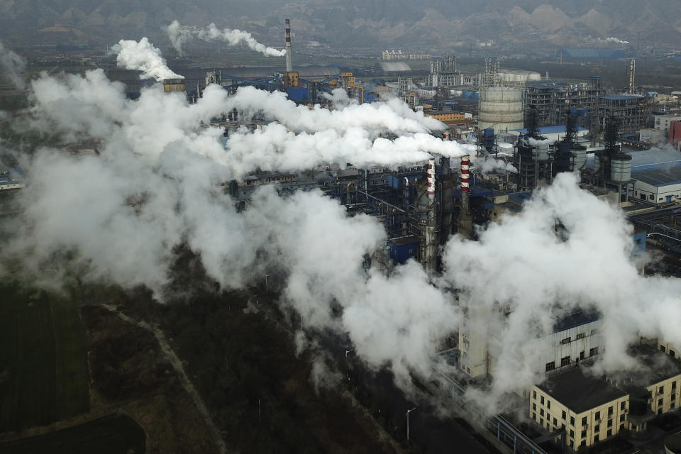 In this Nov. 28, 2019, photo, smoke and steam rise from a coal processing plant that produces carbon black, an ingredient in steel manufacturing, in Hejin in central China's Shanxi Province. As world leaders gather in Madrid to discuss how to slow the warming of the planet, a spotlight is falling on China, the top emitter of greenhouse gases. China burns about half the coal used globally each year. Yet it's also the leading market for solar panels, wind turbines and electric vehicles. (AP Photo/Sam McNeil)
