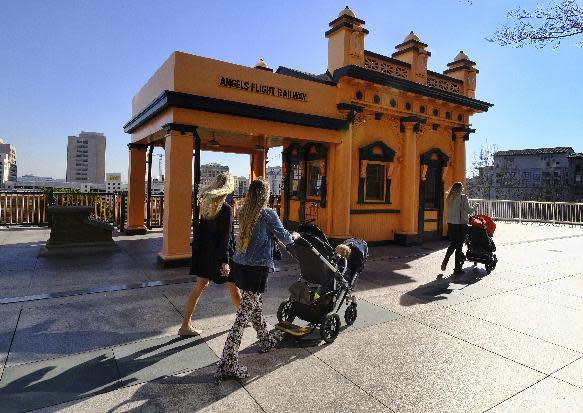 FILE - In this Jan. 17, 2017, file photo visitors walk past Angels Flight Railway in Los Angeles. The tiny funicular that hauled people 298 feet up and down the city's steep Bunker Hill was shut down in 2013 after a series of safety problems. At a news conference Wednesday, March 1, Los Angeles Mayor Eric Garcetti said those issues are being resolved and the railroad's antique wooden cars should be back in service by Labor Day. (AP Photo/Richard Vogel, File)