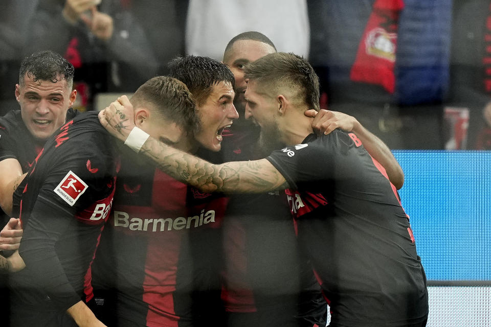 Leverkusen's Patrik Schick, center, celebrates with Leverkusen's Robert Andrich, right, after scoring the decisive goal during the German Bundesliga soccer match between Bayer Leverkusen and TSG Hoffenheim at the BayArena in Leverkusen, Germany, Saturday, March 30, 2024. (AP Photo/Martin Meissner)