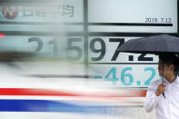 A man stands in front of an electronic stock board showing Japan's Nikkei 225 index at a securities firm as a car passing by in Tokyo Friday, July 12, 2019. Shares in Asia are mostly higher after a turbulent day on Wall Street ended with the Dow Jones Industrial Average closing above 27,000 for the first time. (AP Photo/Eugene Hoshiko)