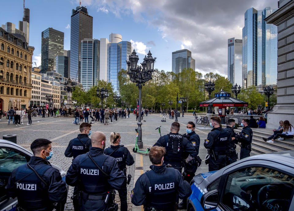 German police officers watch people gathering on the square in front of the Old Opera for drinks and food in Frankfurt, Germany, Friday, May 21, 2021. People left when the police started checking if they stick to the corona restrictions. (AP Photo/Michael Probst)