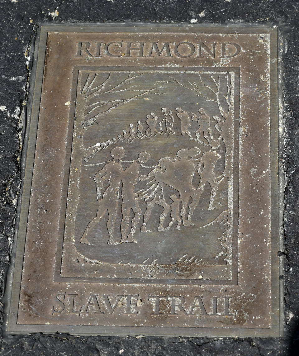 FILE - A historical marker is embedded in the walkway near the Lumpkin Jail historical site at the Slave Burial Ground, March 31, 2014. Richmond, Virginia, has secured an $11 million philanthropic donation to build a new interpretive center city officials hope will someday be part of an ambitious, long-envisioned memorial campus honoring the memory of enslaved people. Richmond’s grant is among more than $16 million in total funding The Mellon Foundation is providing to recipients in the former Confederate capital for projects that are “examining, preserving and reimagining” its “rich historical narratives.” (AP Photo/Steve Helber)