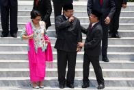 Newly appointed Indonesian Defense Minister Prabowo Subianto, who was the former rival of Indonesian President Joko Widodo in April's election, gestures as he talks with Minister of State Secretariat Pratikno, before taking group photos in Jakarta