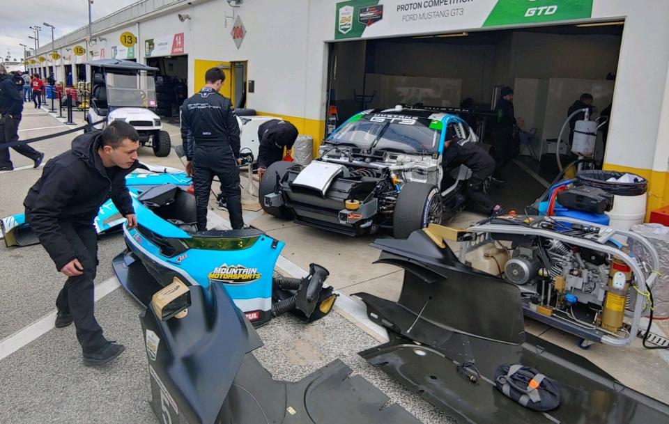 Crew members of Proton Competition's No. 55 Ford Mustang GT3 go through post-qualifying tear-down Sunday in the Daytona garage.