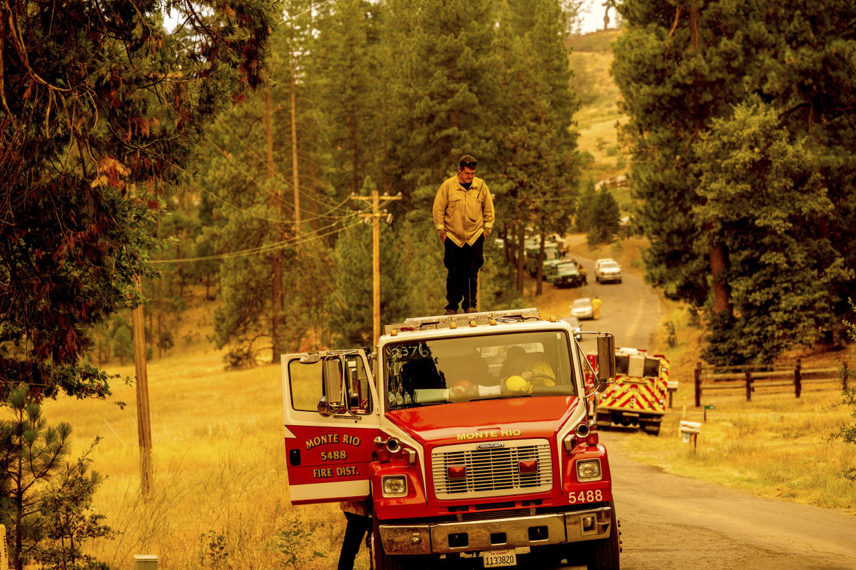 A firefighter stands atop a fire engine shortly after coming on duty to battle the Oak Fire in the Jerseydale community of Mariposa County, Calif., on Sunday, July 24, 2022. (AP Photo/Noah Berger)