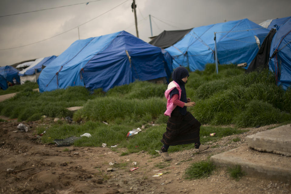 In this March 27, 2019 photo, a girl walks through a tented area at Roj camp, where families of Islamic State supporters are held, near Derik, Syria. The IS could get a new injection of life if conflict erupts between the Kurds and Turkey in northeast Syria as the U.S. pulls its troops back from the area. The White House has said Turkey will take over responsibility for the thousands of IS fighters captured during the long campaign that defeated the militants in Syria. But it’s not clear how that could happen. (AP Photo/Maya Alleruzzo)