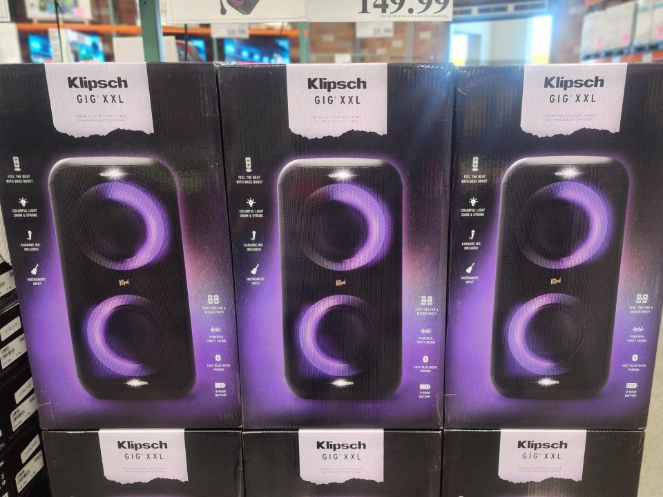 Boxes of Klipsch gig XXL speakers. The boxes are in rows of three and have purple images of speakers on them